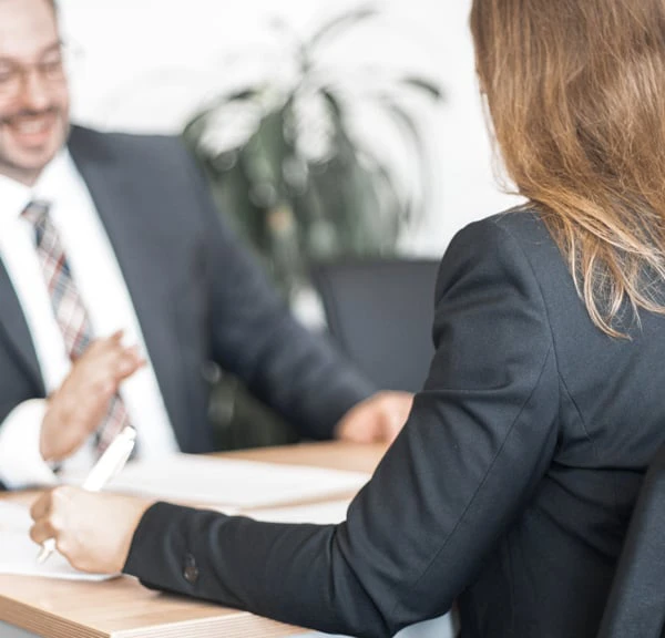 Zwei Personen unterhalten sich über einen Schreibtisch hinweg